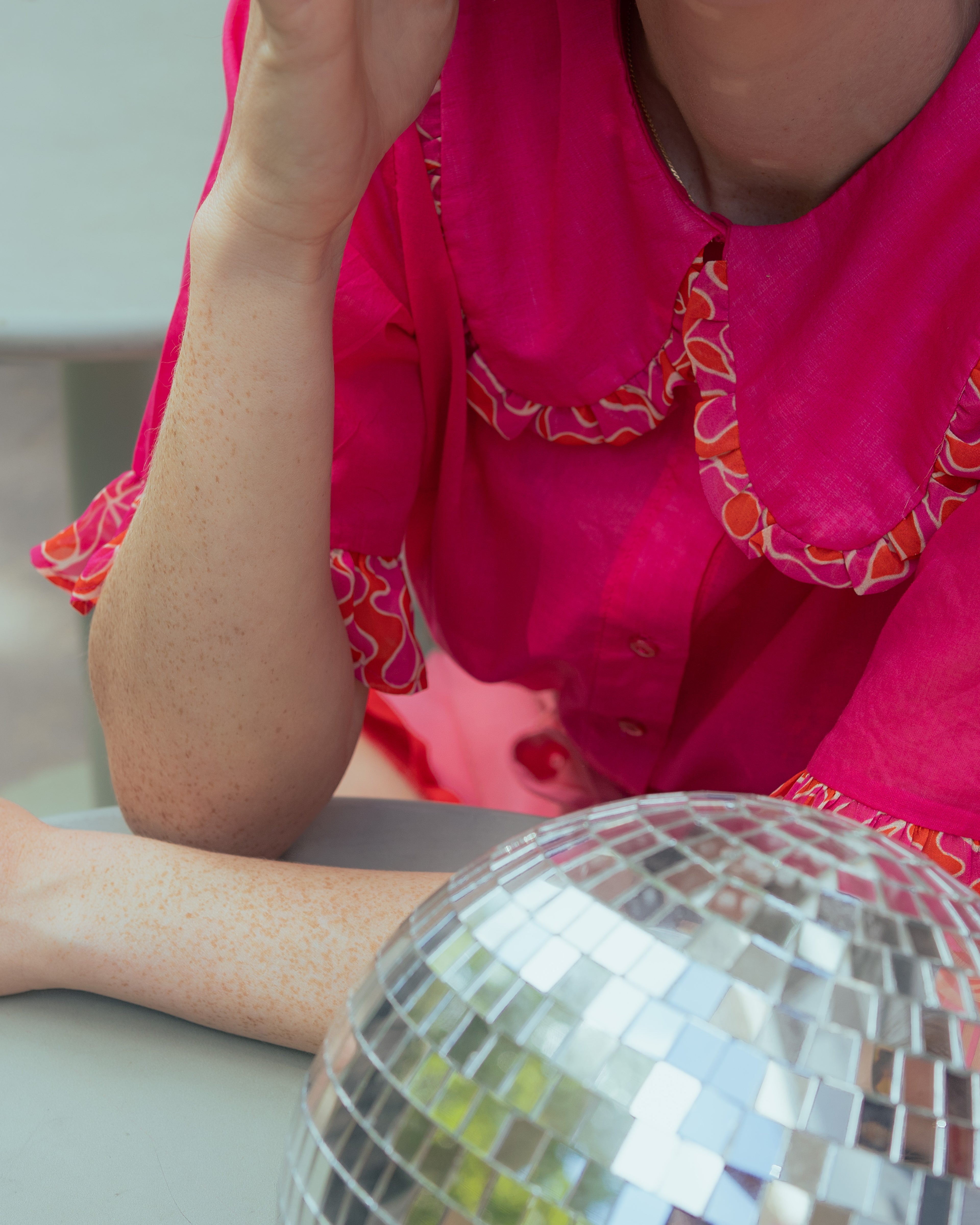 Photo montrant le détail d'un col claudine de la chemisette rose fuschia Te Quiero de Magic Pill Paris, avec une boule à facette. 